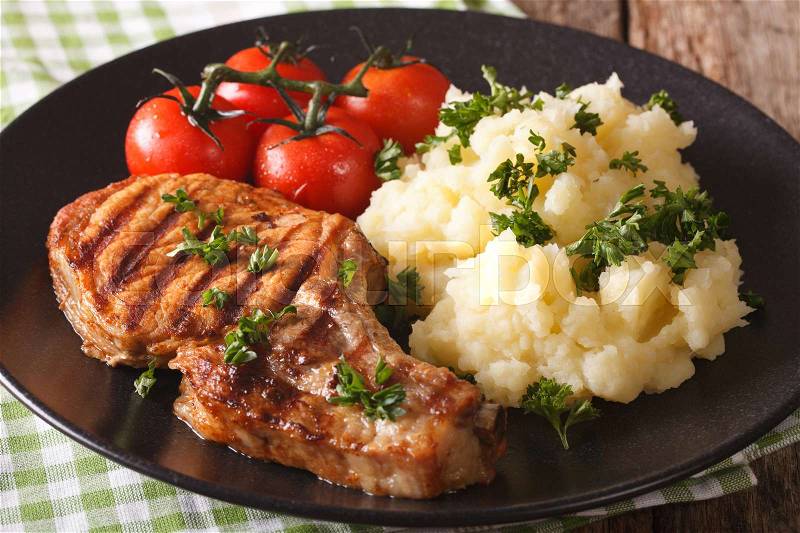 Grilled pork loin with mashed potatoes and tomato close-up on a plate. horizontal , stock photo