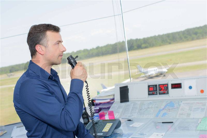Man in control tower talking into microphone, stock photo