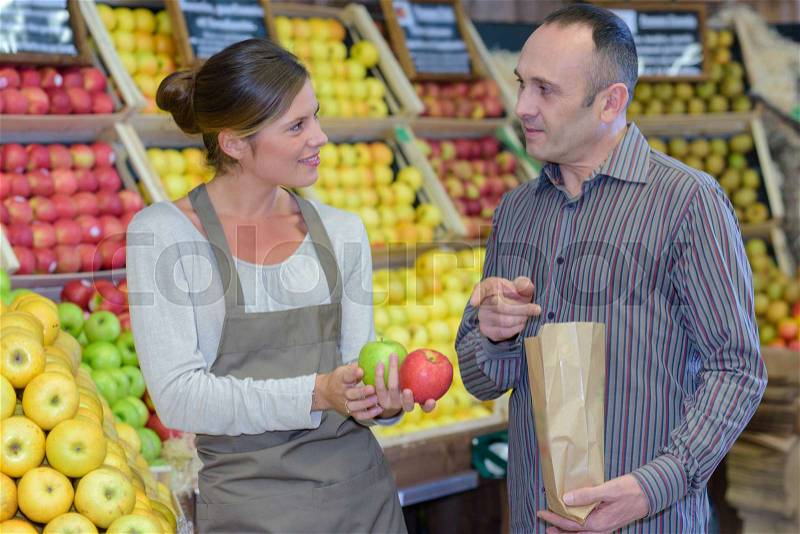 Man buying apples in greengrocers, stock photo