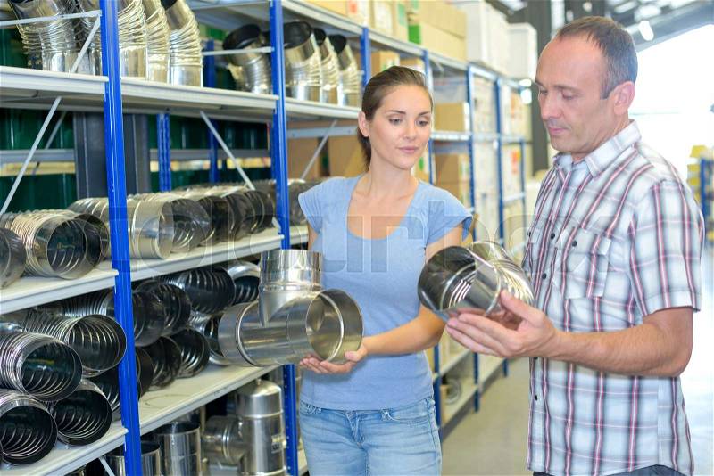 Man and woman in hardware store looking at metal flues, stock photo