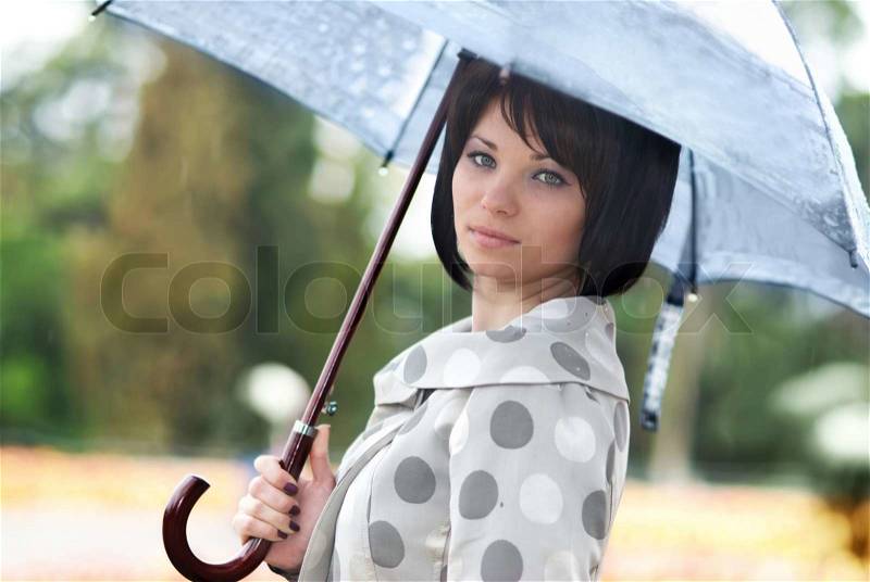 Pretty girl with umbrella in the garden, stock photo