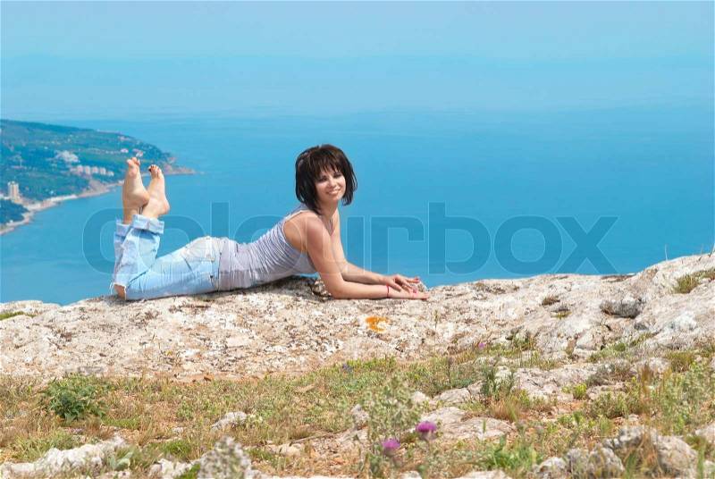 Pretty young woman lying on the rock, stock photo