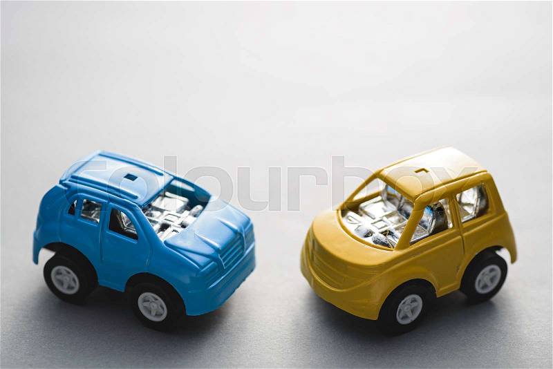 Two small toy car standing on gray background, stock photo
