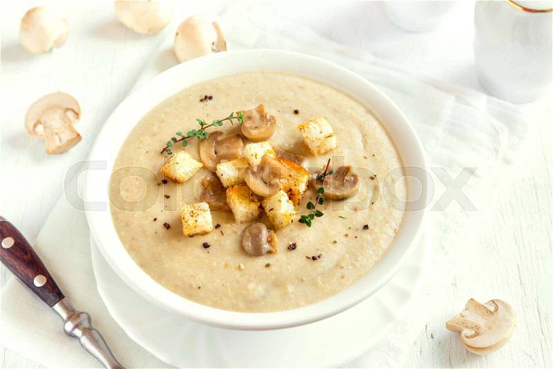 Mushroom cream soup with croutons, herbs and spices over white wooden background with copy space, stock photo