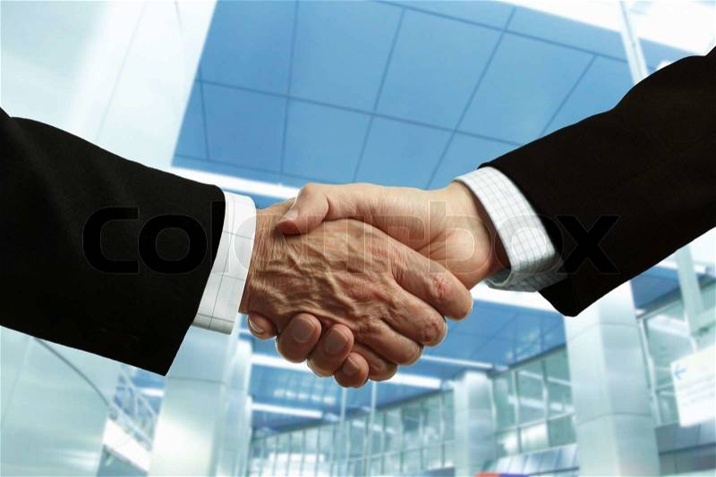 Hand shake of businessmen on corporate building background, focus point on center, stock photo