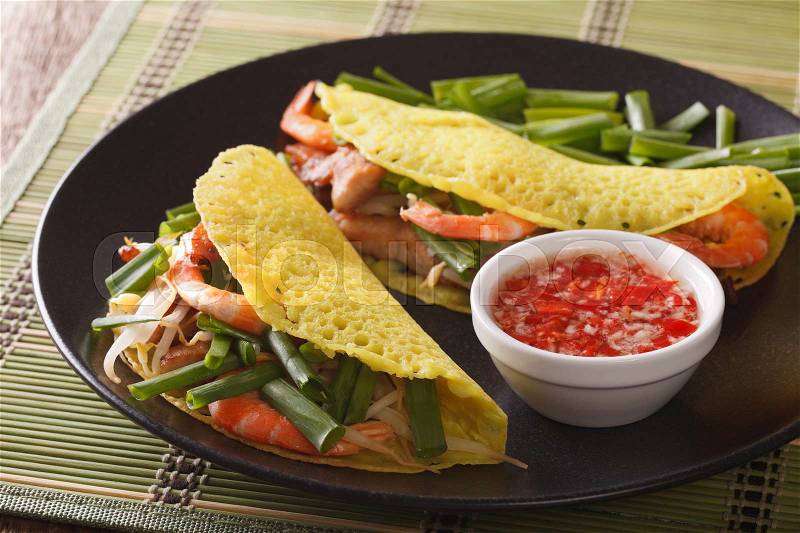 Vietnamese Banh Xeo crepes stuffed with pork, shrimp and bean sprouts and a spicy Nuoc Cham sauce closeup on a plate. horizontal , stock photo
