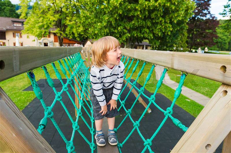 Adorable little by having fun on playground, stock photo