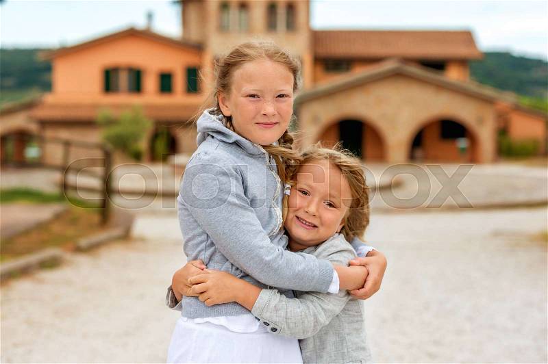 Two adorable kids playing outdoors on a very windy day. Image taken in Tuscany, Italy, stock photo
