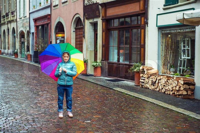Little girl with big colorful umbrella in old town, stock photo