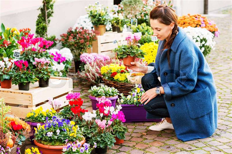 Woman buying flowers in pots in flower shop, stock photo