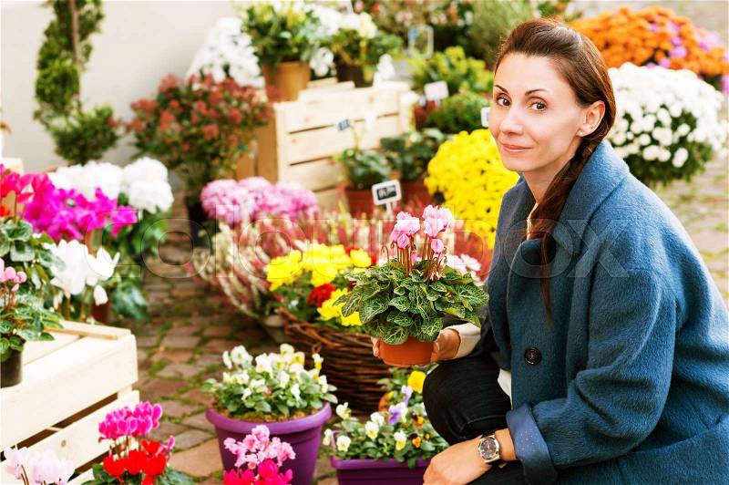 Woman buying flowers in pots in flower shop, stock photo