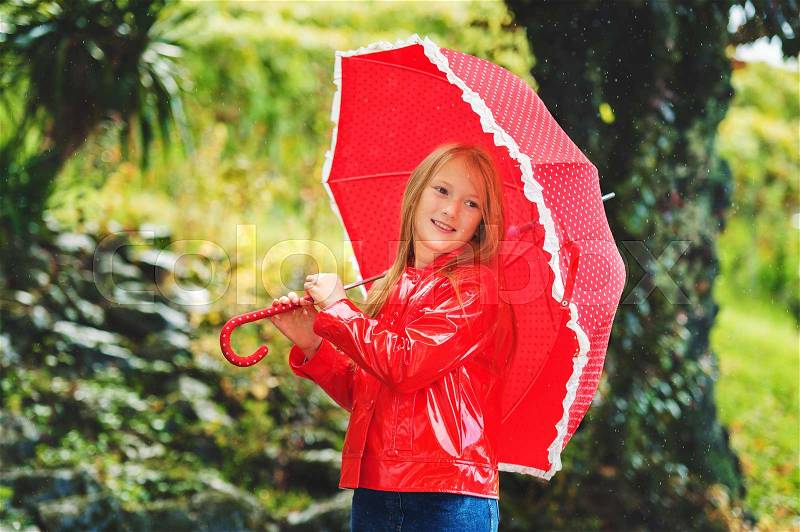 Adorable little girl dancing with umbrella under the rain, wearing red vinyl jacket, stock photo