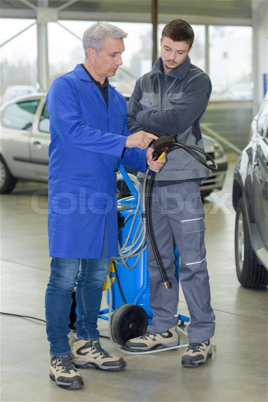 Auto mechanic teacher shows the trainee maintenance of the car, stock photo