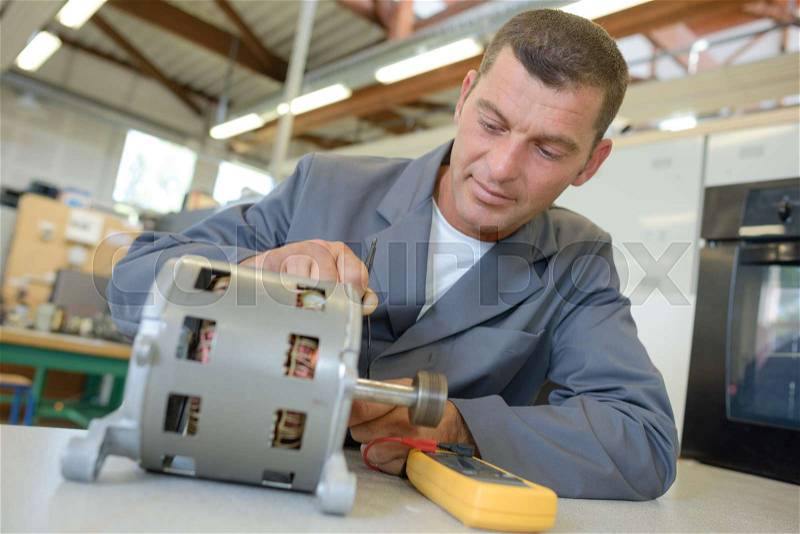 Repairman working on cylindrical electrical component, stock photo