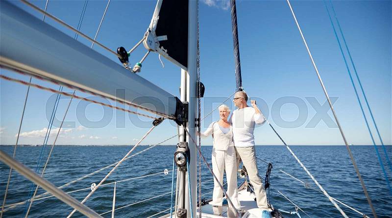 Sailing, age, tourism, travel and people concept - happy senior couple hugging on sail boat or yacht deck floating in sea, stock photo