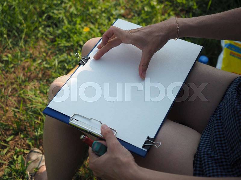 Girl sitting with drawing Board, white sheet of paper. Drawing on the board, stock photo