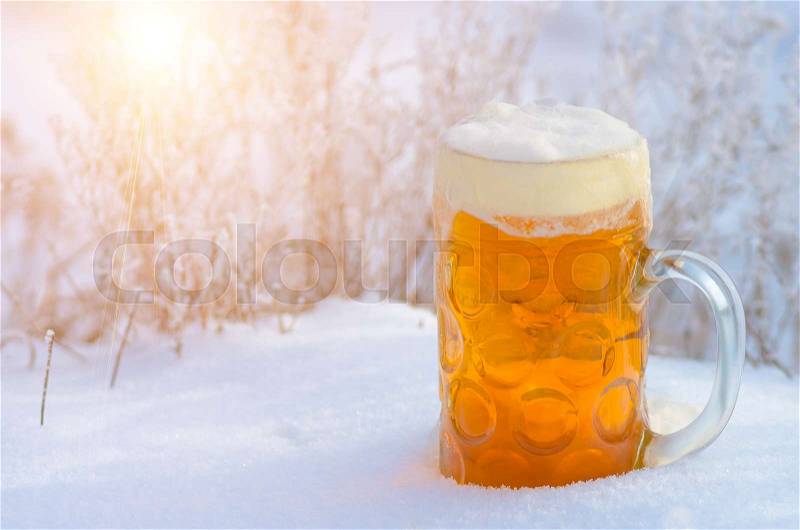 Glass of light beer and foam in the snow in the winter on the nature, beer background, stock photo