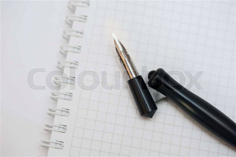 Notebook and a pen for calligraphy on the table, stock photo