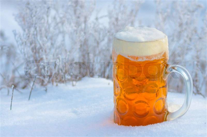 Glass of light beer and foam in the snow in the winter on the nature, beer background, stock photo
