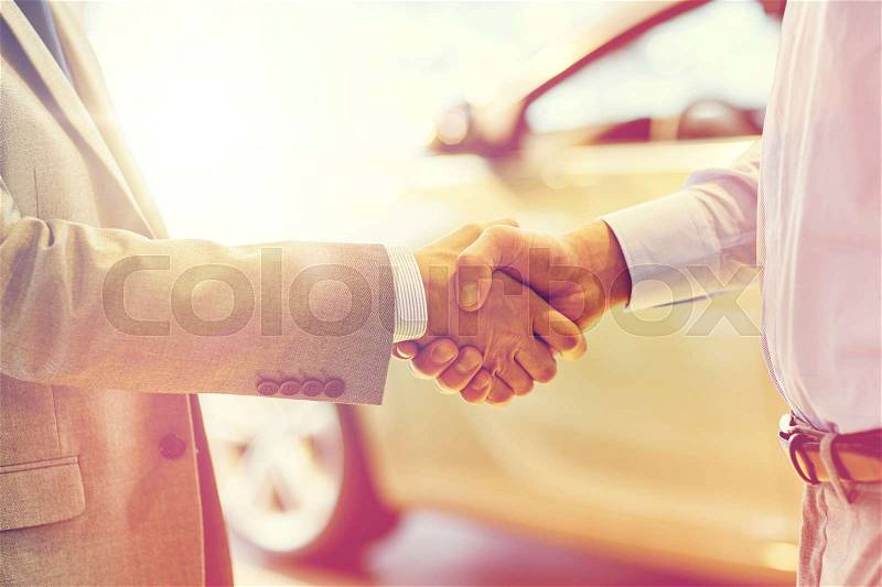 Auto business, car sale, deal, gesture and people concept - close up of male handshake in auto show or salon, stock photo