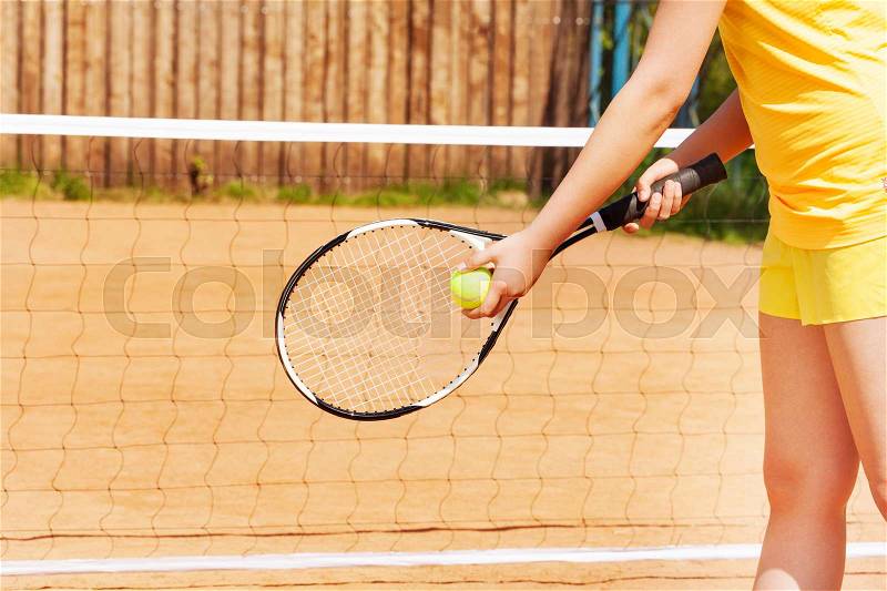 Picture of female player with tennis ball and racket preparing to serve on the clay court, stock photo