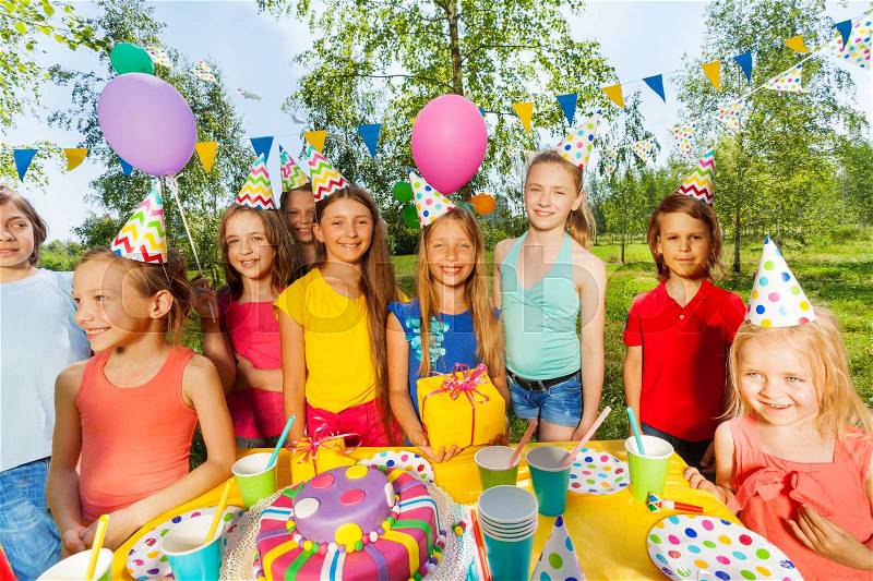 Big group of funny kids congratulating birthday girl at the outdoor party, stock photo