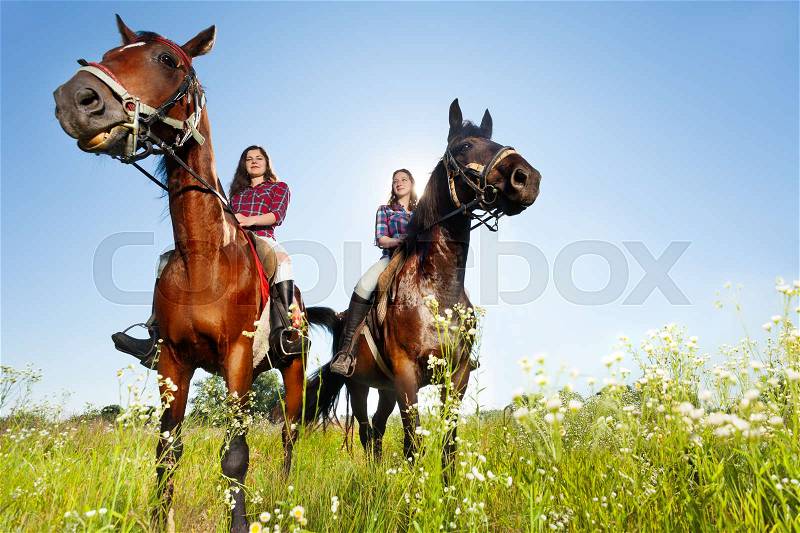 Bottom view portrait of two female equestrians with purebred horses at countryside, stock photo