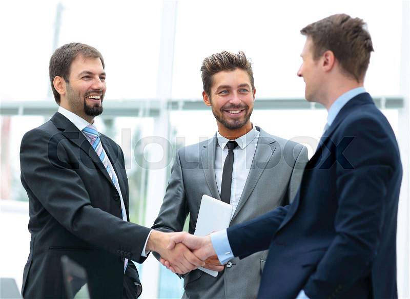 Mature businessman shaking hands to seal a deal with his partner and colleagues in a modern office, stock photo