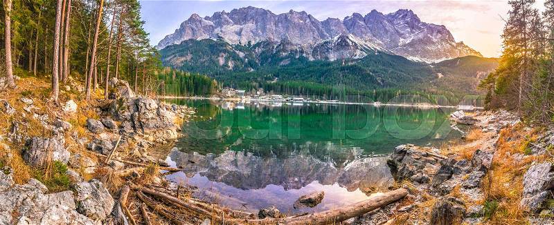 Alpine panorama with the German Alps mountains reflected in the Eibsee lake and green coniferous forest, at sunset in December, stock photo