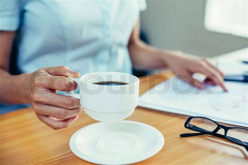 Businesswoman pick up coffee cup from her desk, stock photo