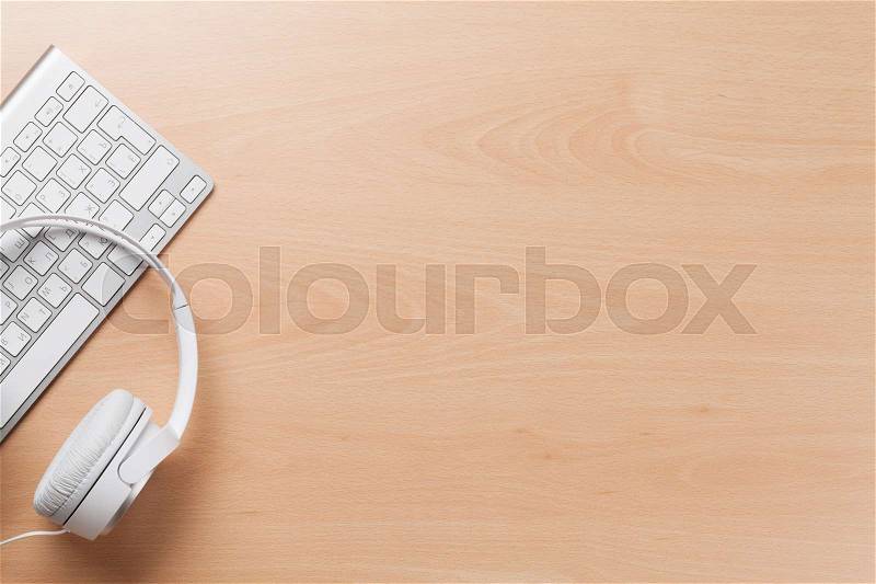 Headphones over pc keyboard on wooden desk table. Music concept. Top view with copy space, stock photo
