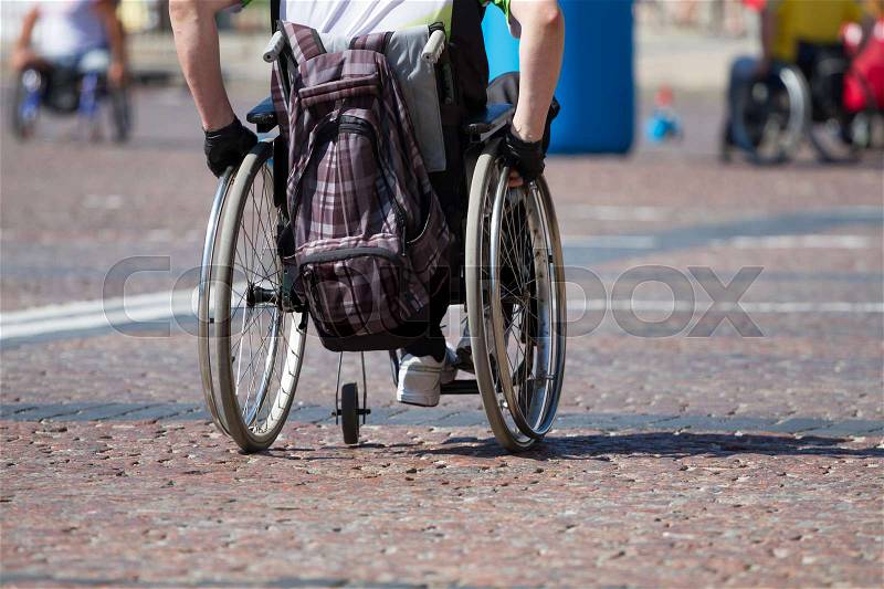Disabled man rides in a wheelchair on the road, stock photo