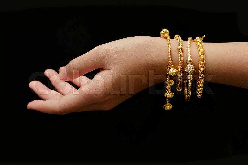 Woman\'s hand with many different golden bracelets on black background, stock photo