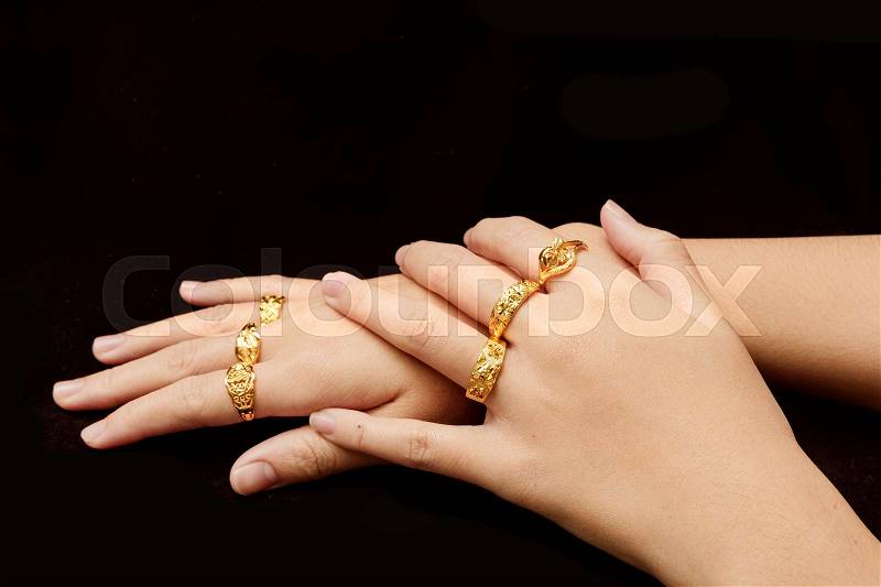 Woman\'s hand with many different gold rings on black background, stock photo