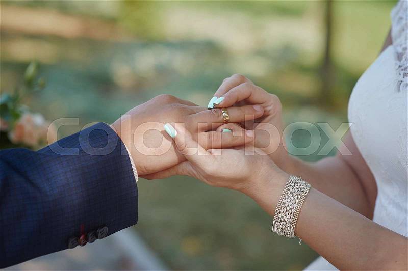 Bride wears a wedding ring on the finger of groom, stock photo