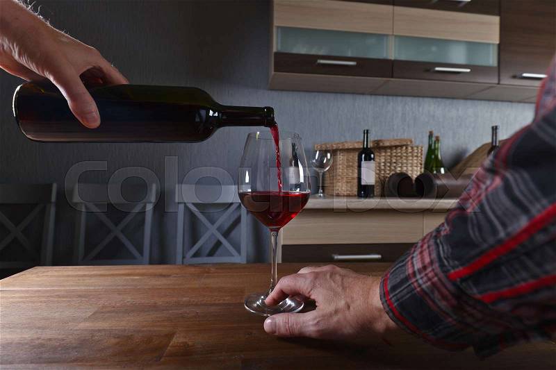 Man pouring red wine into a wineglass, stock photo