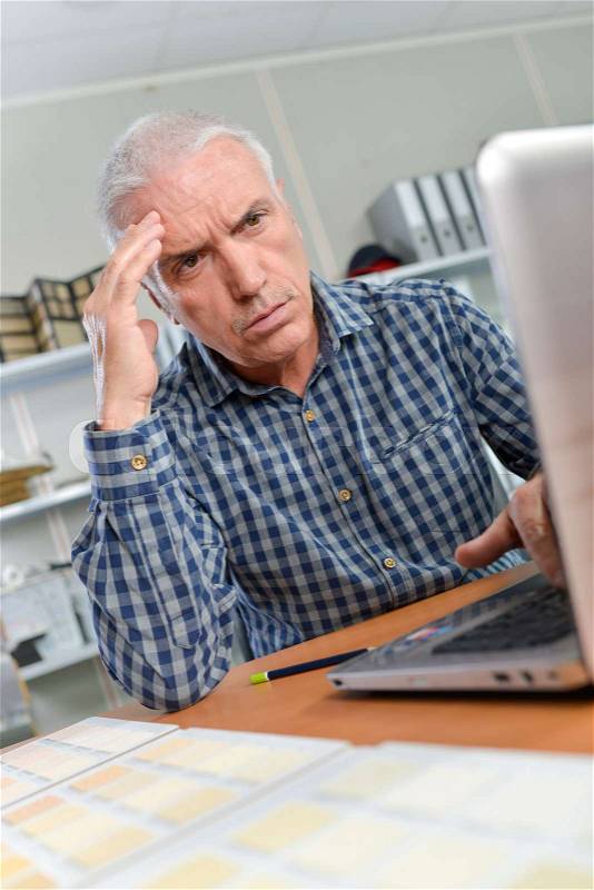 Senior office worker having a few computer issues, stock photo