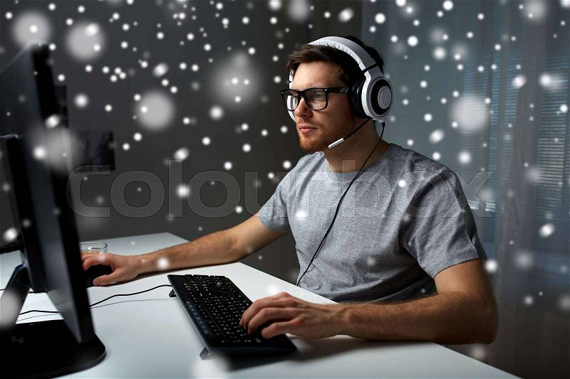 Technology, gaming, entertainment, let\'s play and people concept - young man in headset and glasses with pc computer playing game at home and streaming playthrough or walkthrough video over snow, stock photo