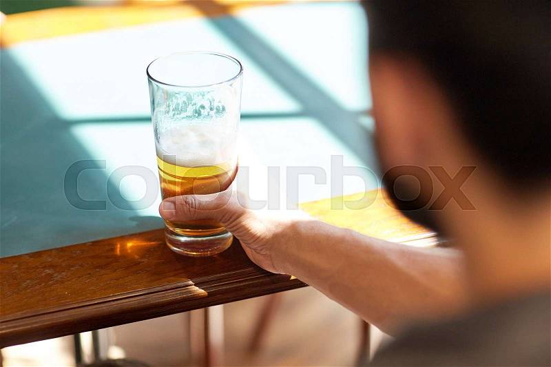People, drinks, alcohol and leisure concept - close up of man drinking beer from glass at bar or pub, stock photo