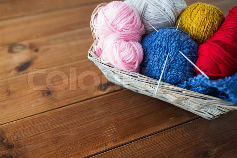 Handicraft and needlework concept - wicker basket with knitting needles and balls of yarn, stock photo