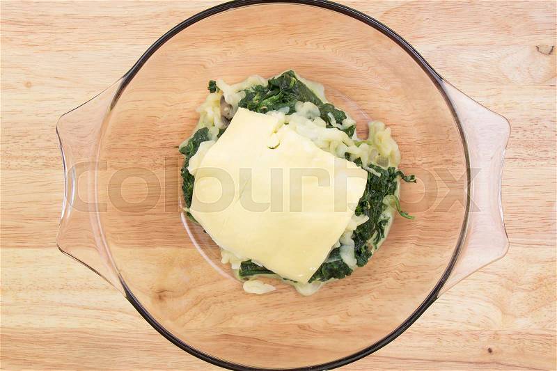 Putting cheese to spinach bowl/ cooking Baked spinach concept, stock photo