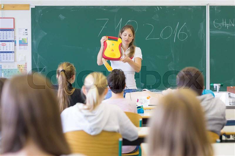 Instructor teaching first aid cardiopulmonary resuscitation course and use of automated external defibrillator workshop in primary school class, stock photo