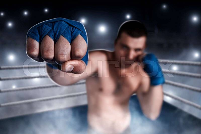 Boxer in blue wrist wraps on the training. Boxing ring on the background. Boxing power, stock photo