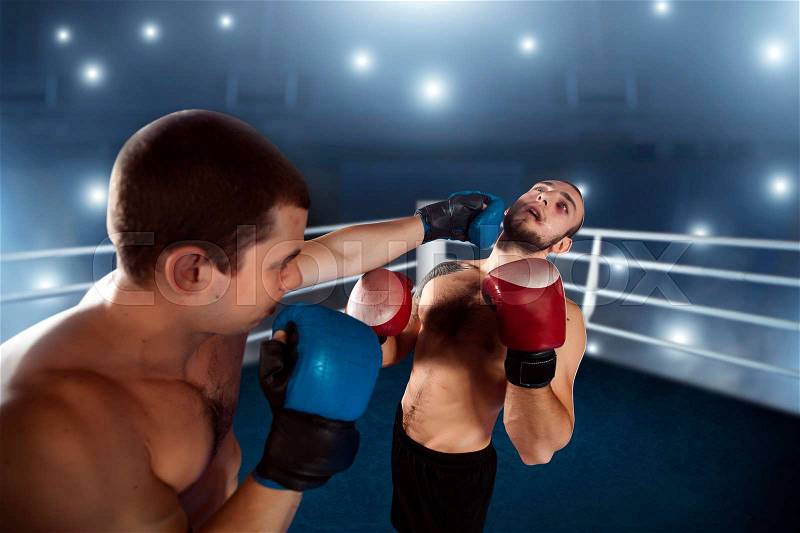 Boxer sents his opponent to the knockout. Fighting ring on the background. Box sport, stock photo