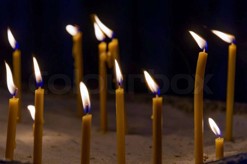 Closeup of bright candles in the dark, stock photo