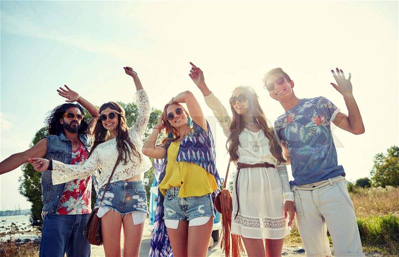 Nature, summer, youth culture and people concept - happy young hippie friends dancing outdoors, stock photo