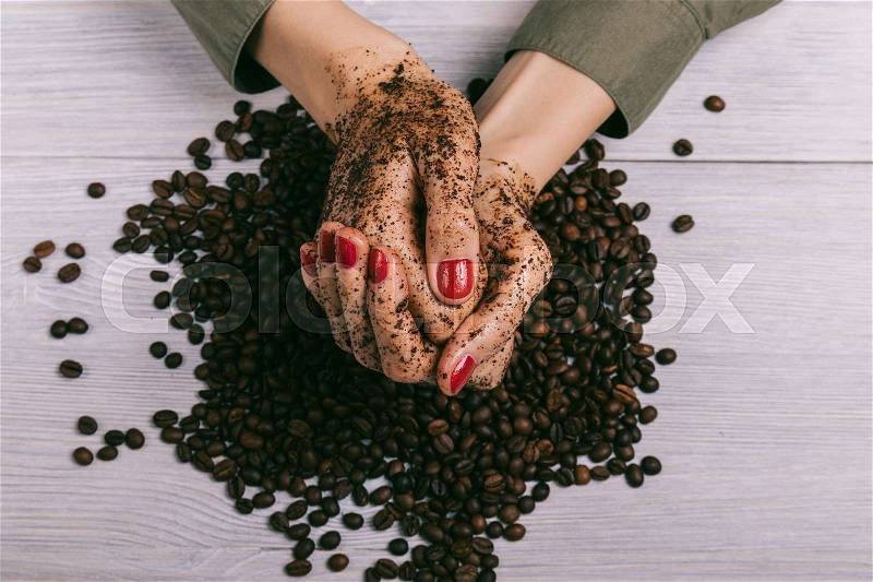 Close-up of female hands coated with scrub and coffee beans, top view, stock photo