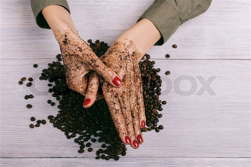Young woman massaging a hand with coffee scrub, top view, stock photo