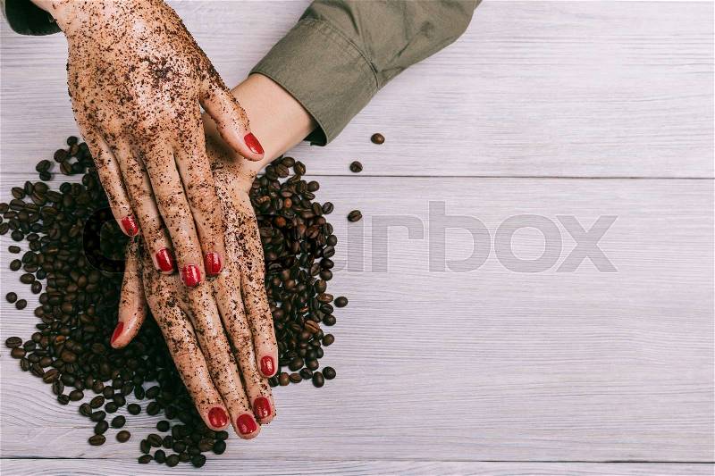 Young woman applies a coffee scrub on hands, top view, copy space, stock photo