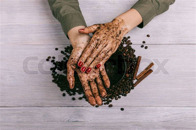 Female hands rubbing the coffee scrub closeup, top view, stock photo